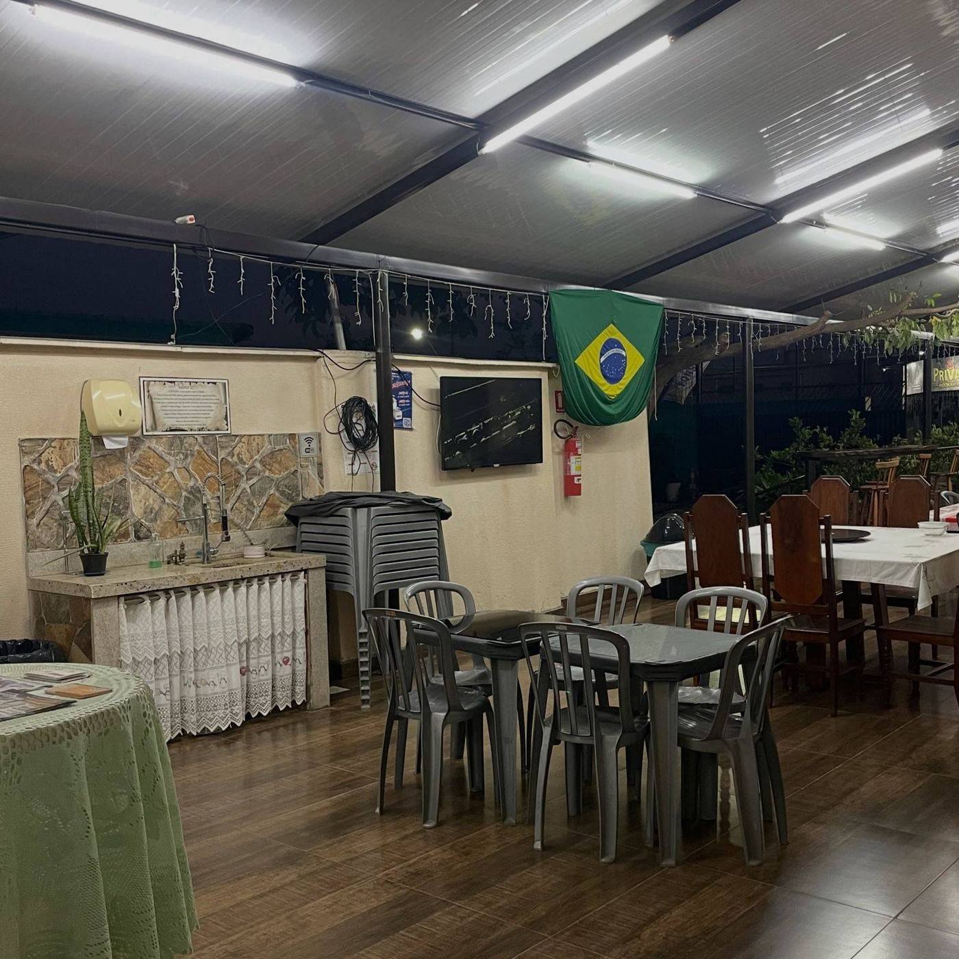 Pátio coberto da Pousada Romeiros, com mesas e TV